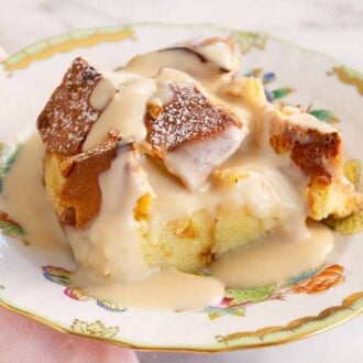 A plate of a serving of bread pudding with vanilla sauce on top.