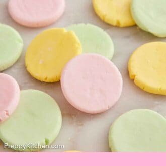 Pinterest graphic of multi-colored butter mints flattened into circles on a marble surface.