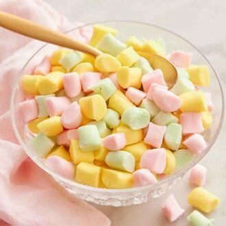 A bowl of butter mints with a spoon inside.