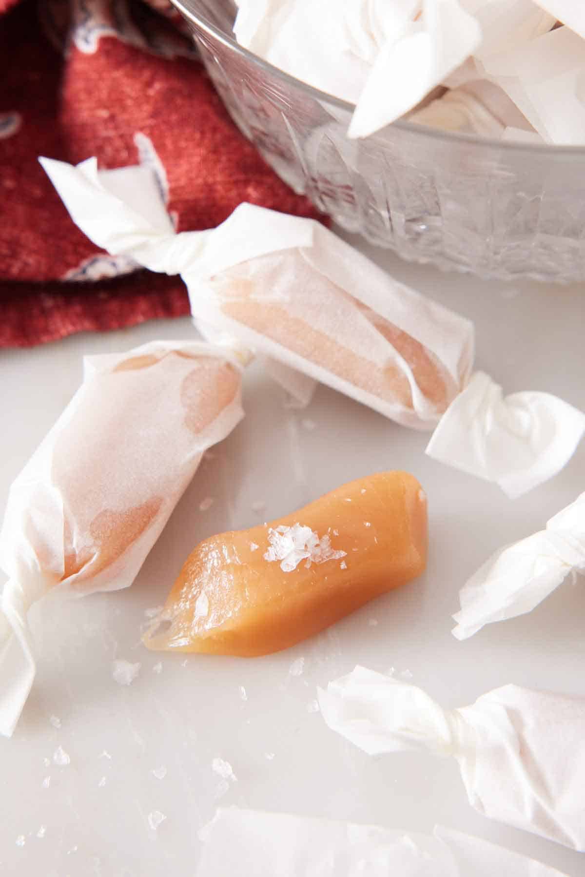 Three pieces of caramels with two of them wrapped in paper.