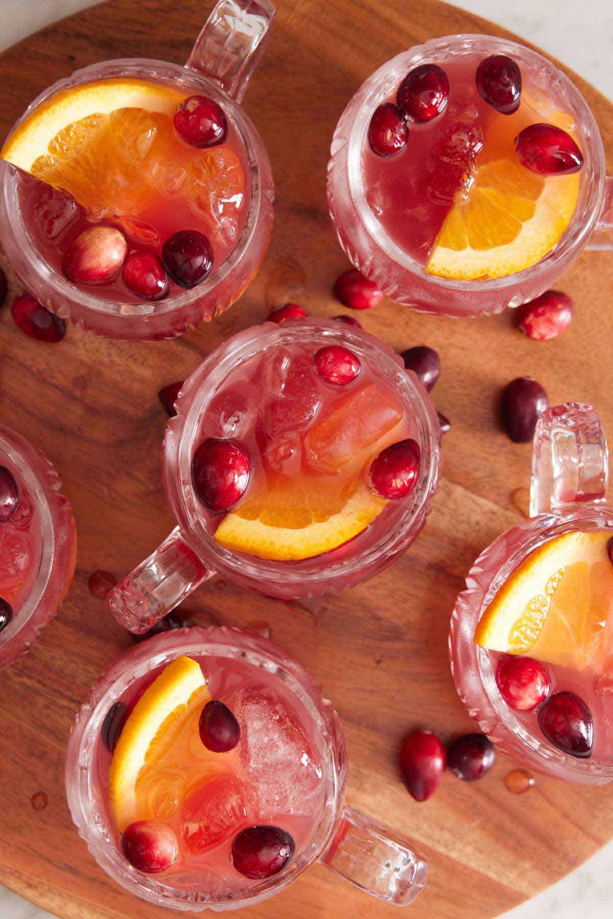 Overhead view of multiple glasses of Christmas punch with cranberries scattered around.