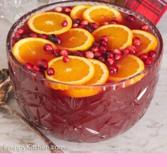 Pinterest graphic of a glass punch bowl of Christmas punch topped with fresh orange slices and cranberries.