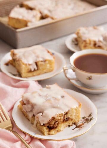 Multiple plates with sliced cinnamon roll cake with a mug of coffee.