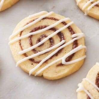 A cinnamon roll cookie with icing drizzled on top.