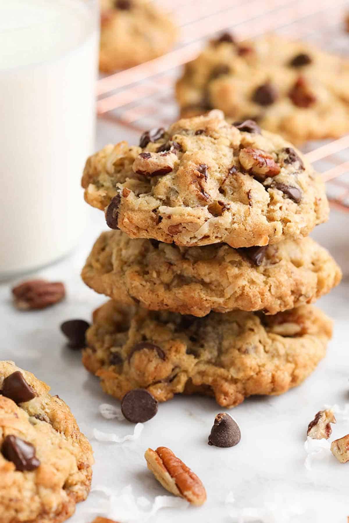 A stack of three cowboy cookies with additional ingredients scattered around.