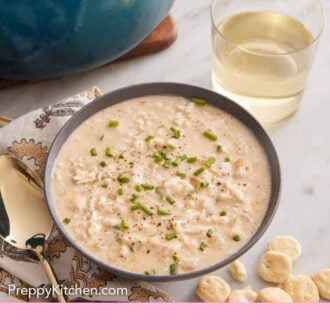 Pinterest graphic of a bowl of crab soup with a drink and pot with the rest of the soup in the background.