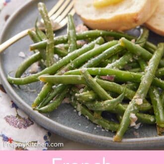 Pinterest graphic of French green beans on a plate with a fork and bread with some butter on it.