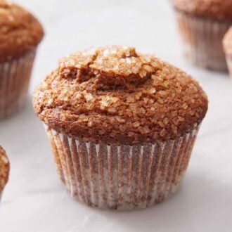 Multiple gingerbread muffins on a marble surface with one in focus.
