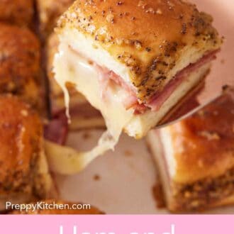 Pinterest graphic of a ham and cheese slider lifted from a baking dish with melted cheese being pulled up from it.