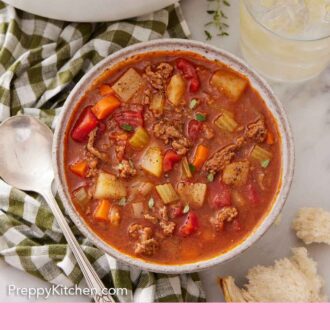 Pinterest graphic of an overhead view of a bowl of hamburger soup with a drink beside it.