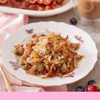 Pinterest graphic of hash browns on a plate. Coffee and bacon strips in the background.