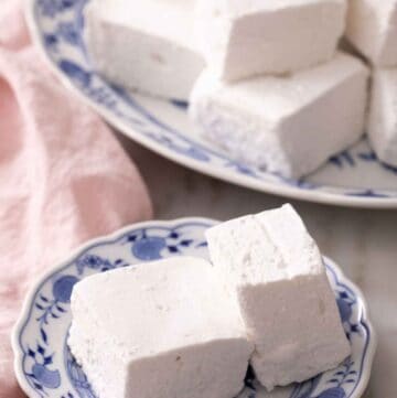 A plate with two homemade marshmallows with a platter in the background.