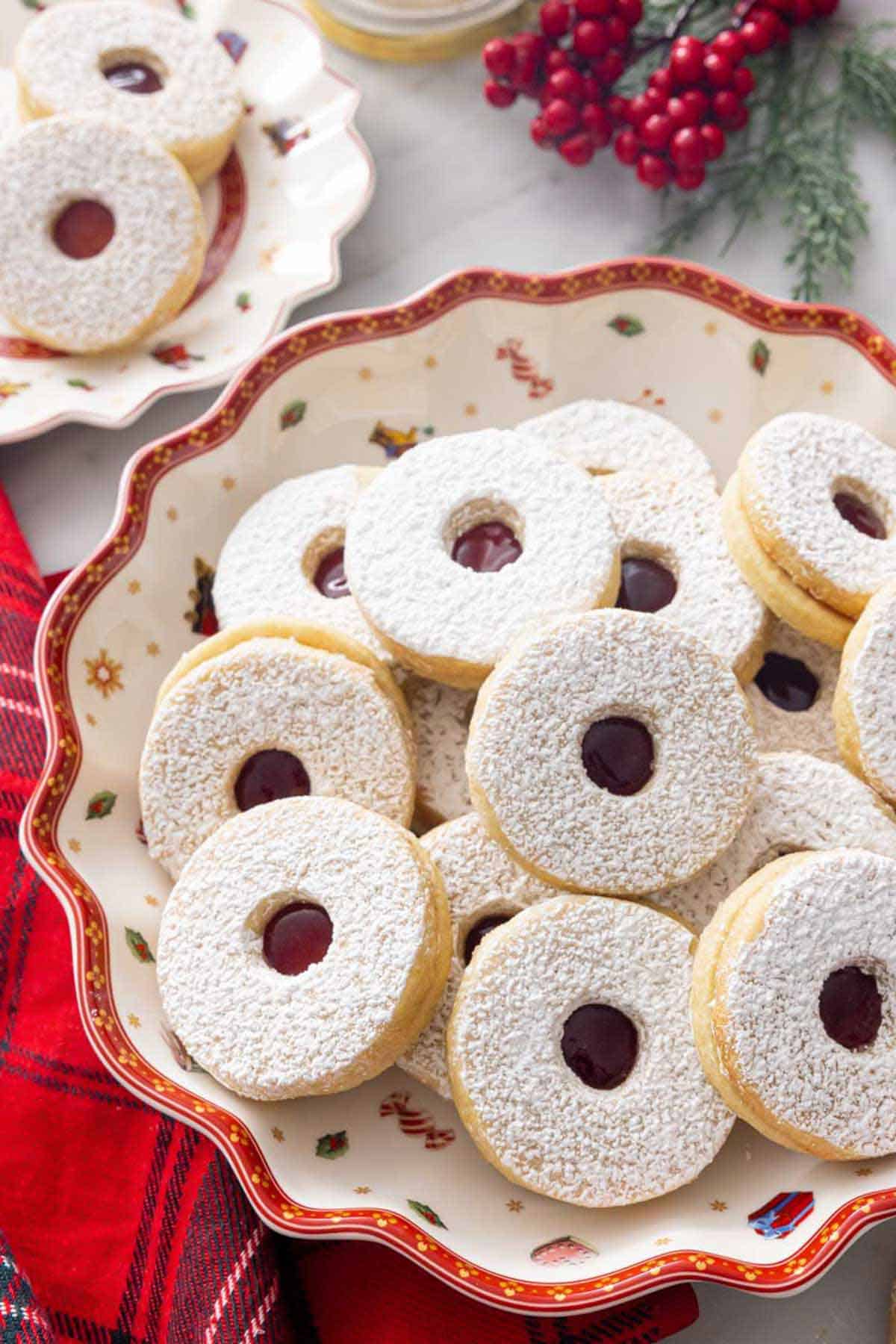 A platter of multiple linzer cookies with more in the background.