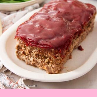 Pinterest graphic of a platter of with a loaf of meatloaf with some green beans in the background.