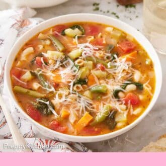 Pinterest graphic of a bowl of minestrone soup with one other in the back, topped with parmesan cheese.