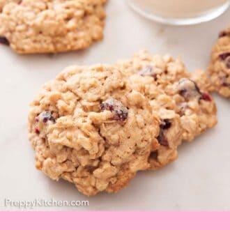 Pinterest graphic of oatmeal cookies on a marble surface with a glass of milk in the background.