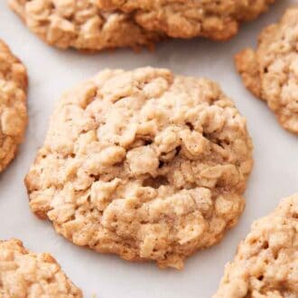 Multiple oatmeal cookies on a marble surface.