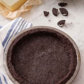 Pinterest graphic of an overhead view of an Oreo pie crust and some crushed Oreos, butter, and whipped topping in the background.
