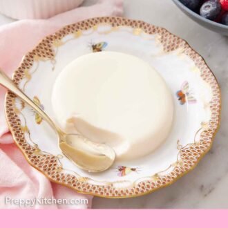 Pinterest graphic of a serving of panna cotta with a spoon in front of a bite taken.