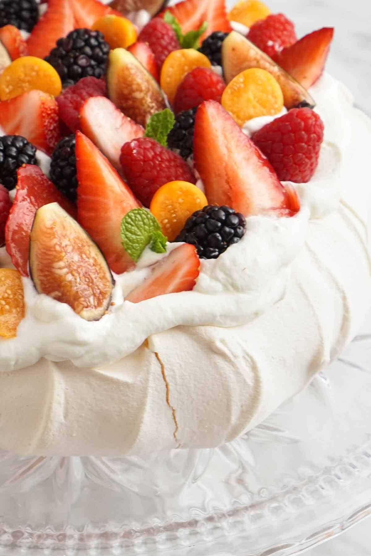 A close up view of a pavlova topped with fresh berries.