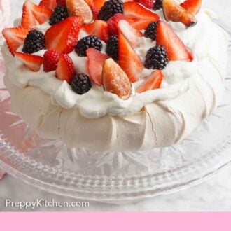 Pinterest graphic of a pavlova on a cake stand topped with whipped cream and berries.
