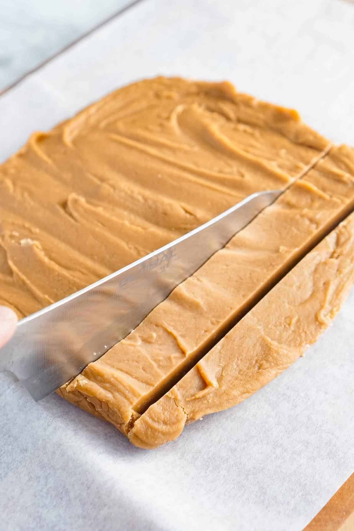 A slab of peanut butter fudge being sliced with a knife.