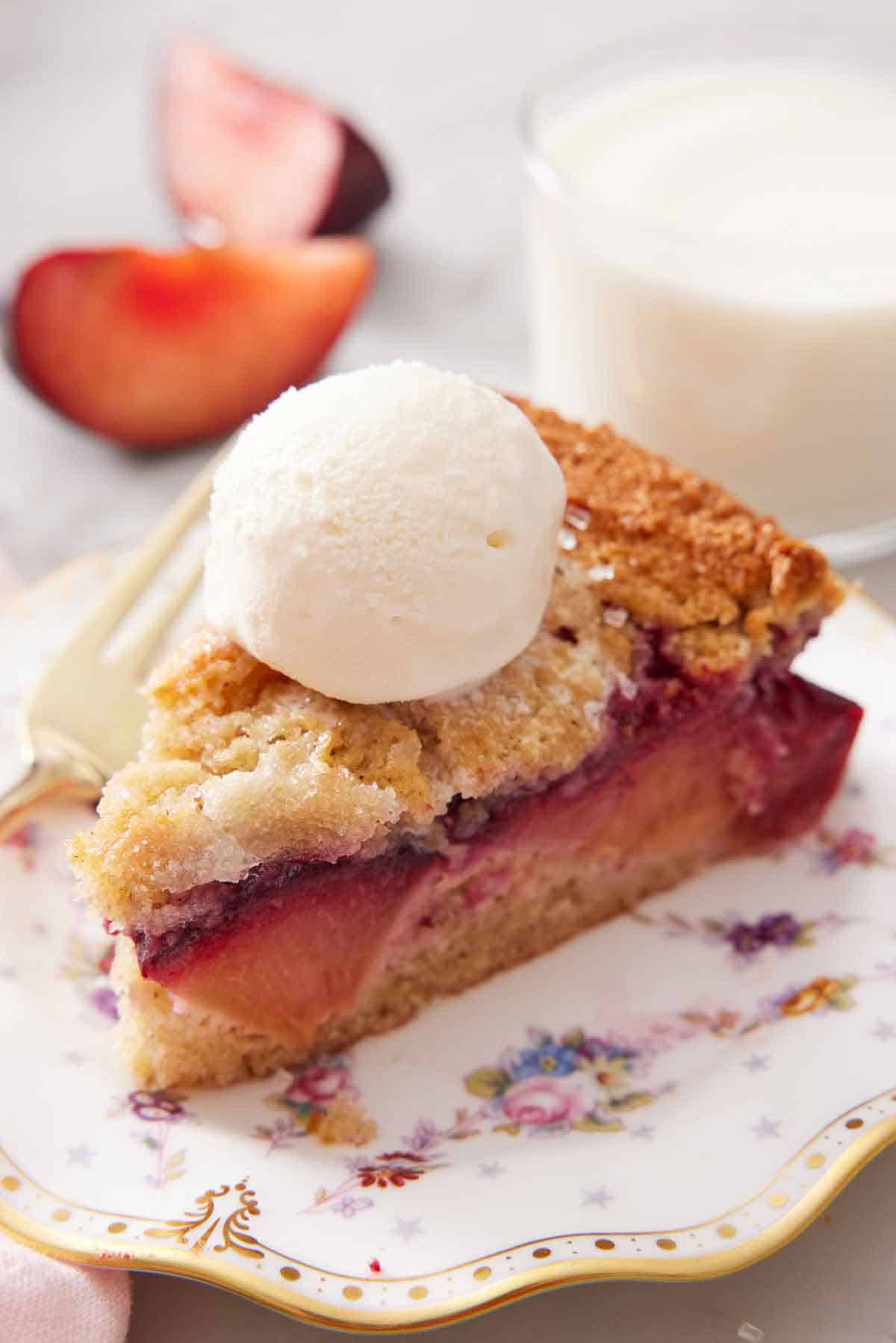 A plate with a slice of plum cake topped with a scoop of ice cream.
