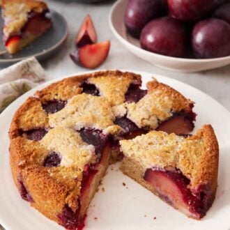 Pinterest graphic of a platter with a cut plum cake with one slice cut and still on the platter.