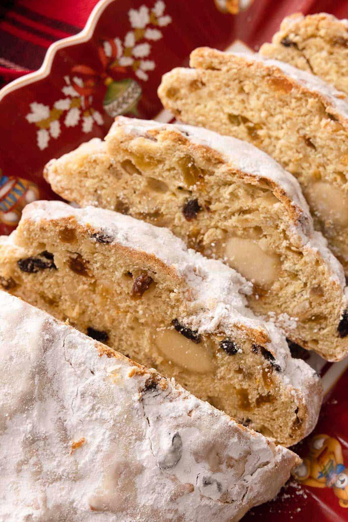A loaf of stollen, sliced, showing the interior of the slices, dotted with rum soaked fruit.
