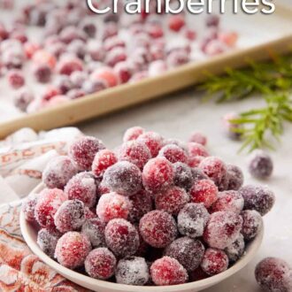 Pinterest graphic of a bowl of sugared cranberries with a sheet pan with more in the background.