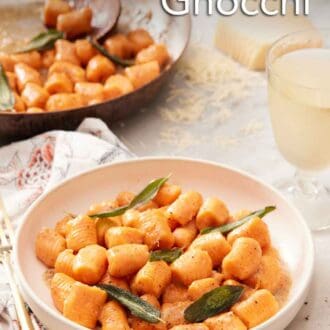 Pinterest graphic of a plate with a serving of sweet potato gnocchi with sage leaves. A skillet of sweet potato gnocchi in the background.
