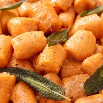 A close up view of sweet potato gnocchi topped with sage.