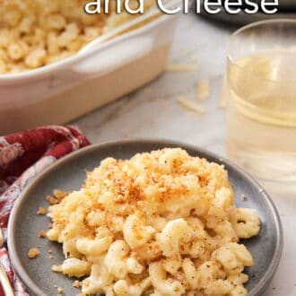 Pinterest graphic of a plate with a serving of truffle mac and cheese with a baking dish and glass of wine in the background.