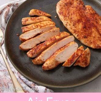 Pinterest graphic of a plate with two air fryer chicken breasts, one breast sliced.