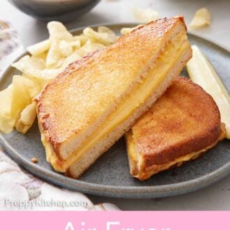 Pinterest graphic of a plate with an air fryer grilled cheese cut in half on a plate along with chips and a pickle.