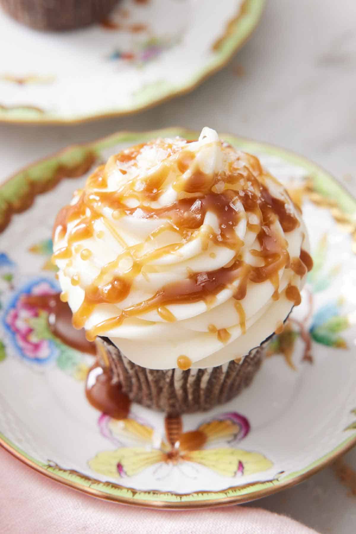A cupcake with drizzled butterscotch over the frosting.