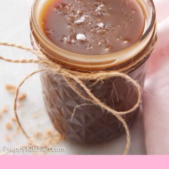 Pinterest graphic of a jar of butterscotch with a twine bow tied on and flaky sea salt on top.