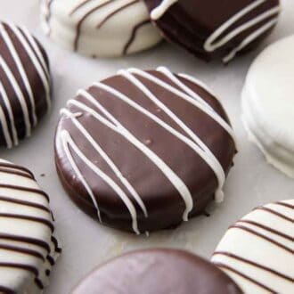 Chocolate covered oreos in a single layer on a marble counter.