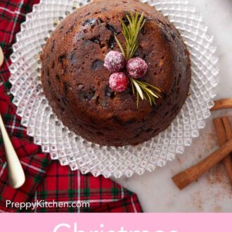 Pinterest graphic of an overhead view of a Christmas pudding on a platter with three sugared cranberries and rosemary on top.