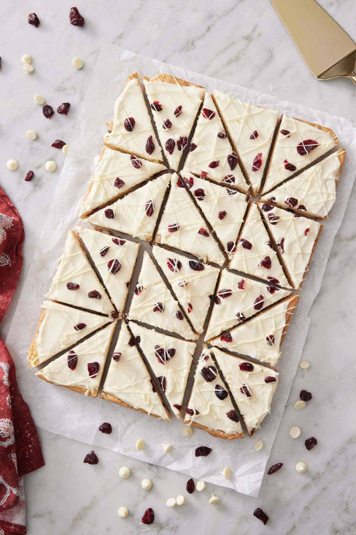 Overhead view of cranberry bliss bars on a parchment paper over a marble counter.