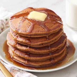 A plate with a stack of gingerbread pancakes with butter and syrup.