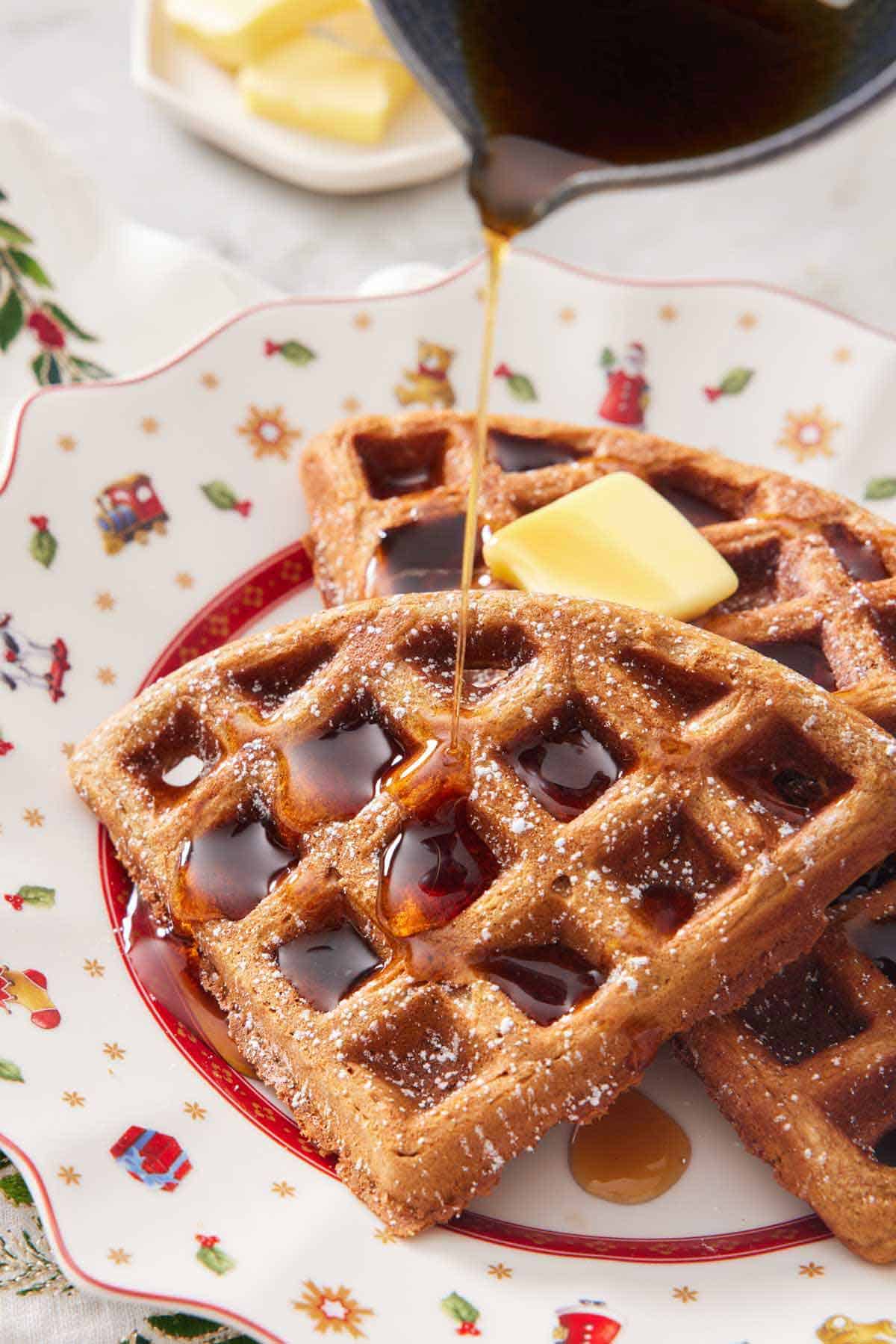 Syrup poured over gingerbread waffles on a plate.
