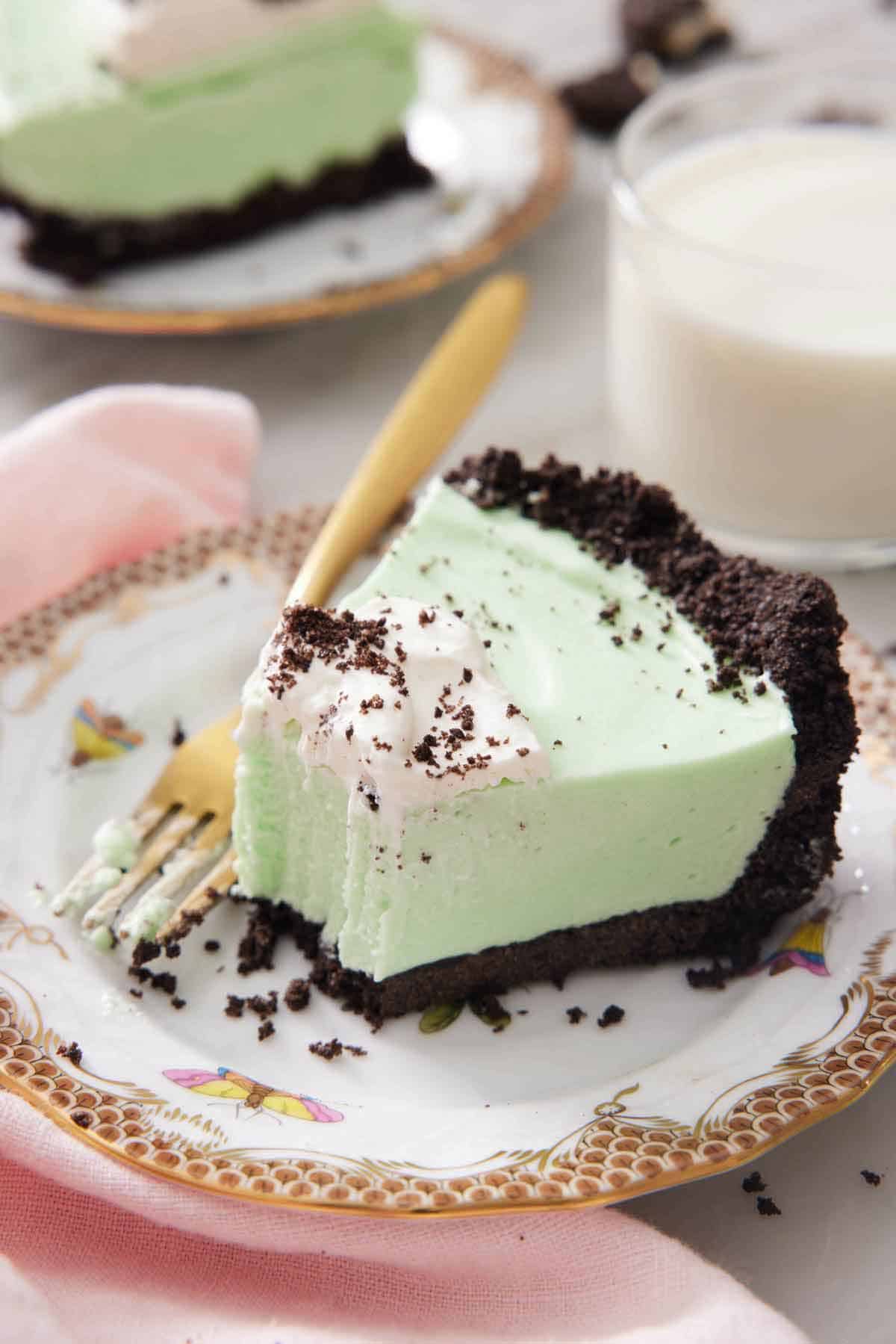 A slice of grasshopper pie on a plate with a bite taken out of it.