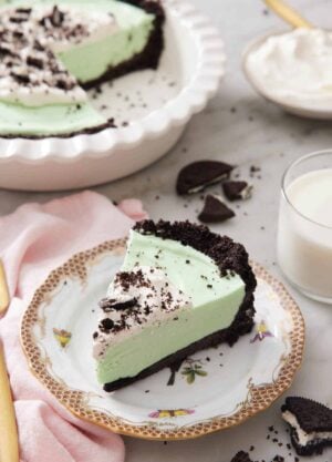 A slice of grasshopper pie on a plate with the rest in a baking dish in the background.
