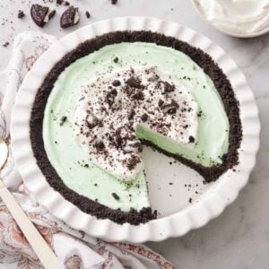 Overhead view of a baking dish with a grasshopper pie with a slice removed.