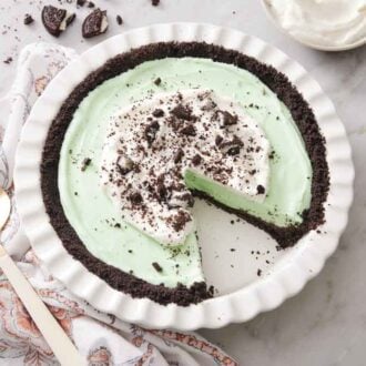 Overhead view of a baking dish with a grasshopper pie with a slice removed.