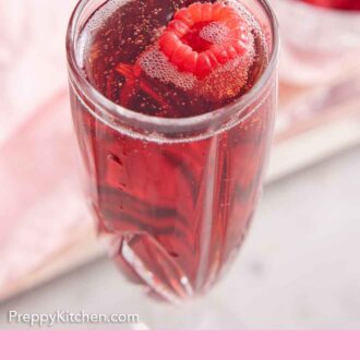 Pinterest graphic of a glass of Kir Royale with a fresh raspberry floating on top.