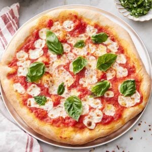 A cheese pizza topped with basil.