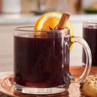 Pinterest graphic of a glass of mulled wine with a cinnamon stick and orange slice garnish.