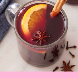 Pinterest graphic of a slightly overhead view of a glass of mulled wine garnished with cinnamon stick, orange slice, and star anise.